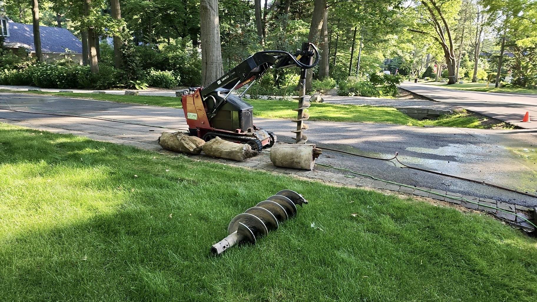 A small tractor is parked on the grass near some trees.